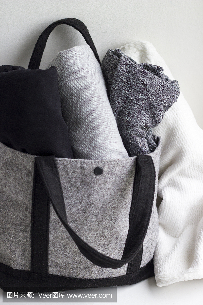 特写衣服卷在羊毛灰色袋子在白色的背景。